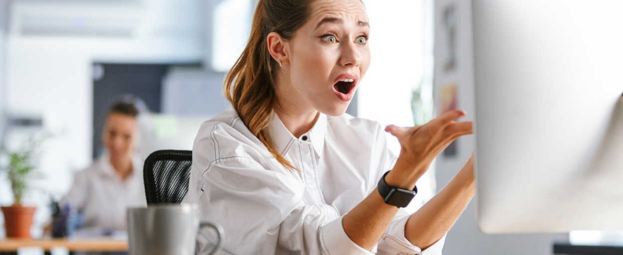 A person looking surprised in front of a computer screen