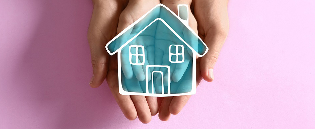 Two hands coming together to hold a drawing of a blue house with a pink background