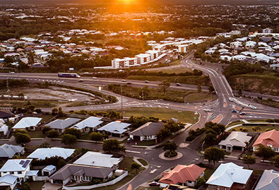 Aerial shot over Townsville suburban houses with sunsetting in background